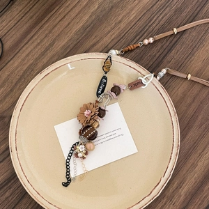 Close-up of bohemian pendant with floral fabric, faux pearls and Believe tag