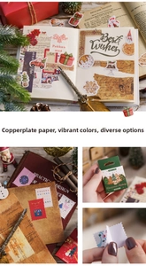 Close-up of Christmas stickers on scrapbook with pine cones and vintage quill pen