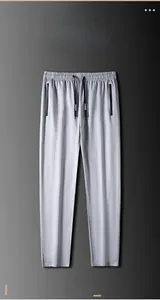 Detalle de pantalones deportivos grises con cintura elástica y bolsillos con cremallera