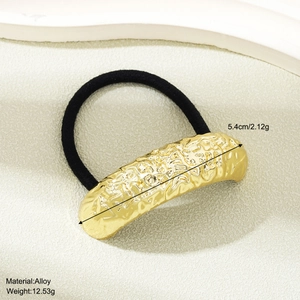 Detail of golden alloy hair ring with hammered texture and black elastic band