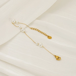 Minimalist gold stainless steel pearl bracelet with lobster clasp on white silk fabric