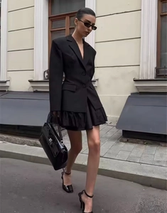 Street view of a black long-sleeved jacket suit with lace details and a ruffled skirt