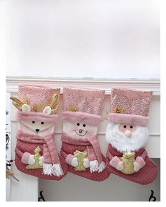 Detailaufnahme von drei rosa Weihnachtssocken mit Pailletten, Rentier-, Schneemann- und Weihnachtsmann-Motiven