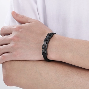 Detail of men's matte black chain and braided leather bracelet on model wrist