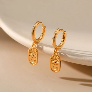 Detail of 18K gold plated hoop earrings with engraved sun and smiley face pendant tags