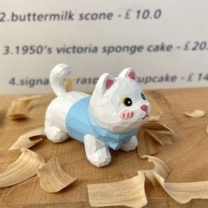 Détail de la figurine de chat en bois sculpté à la main avec chemise bleue et copeaux