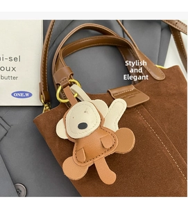 Detail der braunen Wildleder-Beuteltasche mit Kontrastnähten und einem Leder-Affenanhänger