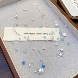 Détails du collier de plage argenté avec perles bleues et étoile de mer sur plateau en lin