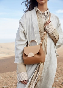 Detail of two-tone tan and beige leather handbag with gold-tone hardware and pebble texture