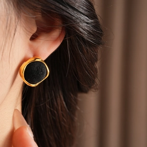 Vue détaillée d'élégantes boucles d'oreilles noires à bordure dorée portées par un mannequin