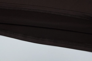 Detalle de costura doble de alta calidad en la tela oscura de un vestido de estilo francés