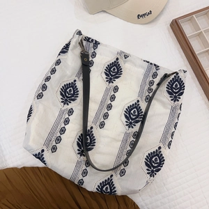 Detail of bohemian floral embroidery on white cotton linen tote with black leather strap