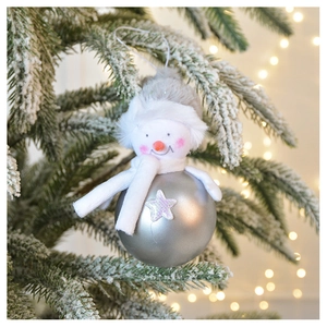 Close-up of plush snowman ornament with silver star ball on a snowy Christmas tree branch