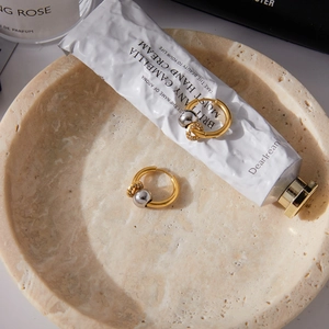Detail of 18K gold and silver two-tone hoop earrings with crystal pavé charm on stone tray