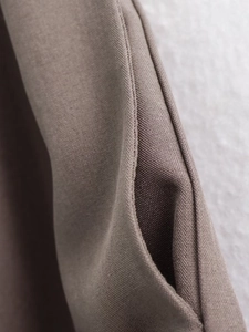 Macro shot of side seam craftsmanship and pocket edge on dark brown woven trousers