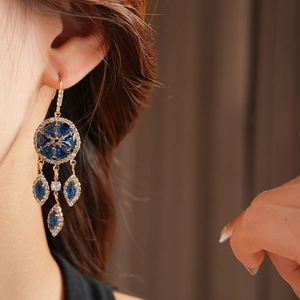 Close-up of vintage gold snowflake earrings with blue stones on model's ear