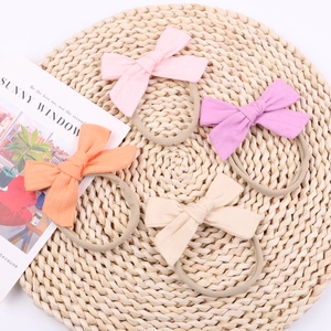 Dettaglio di quattro fasce per neonati in nylon morbido con fiocchi in colori pastello