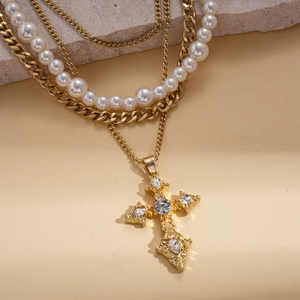 Detailed close-up of multilayer gold necklace with pearls and rhinestone cross pendant