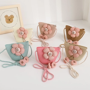Detail of colorful children straw crossbody bags with 3D fabric flowers and pom-poms