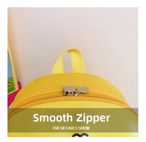Close-up of a yellow kids backpack with dual metal zippers and a top carry handle