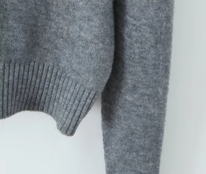 Detailed macro view of the grey ribbed knit cuffs and plush texture of the cardigan