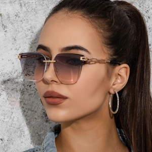 Close-up of frameless gradient sunglasses with gold metal chain temple on model