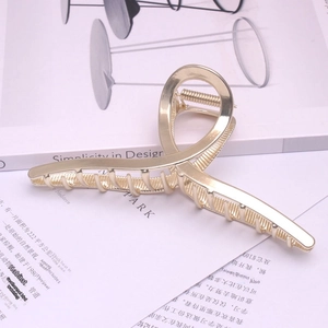 Macro shot of large golden metal claw clip with a polished finish on a book background