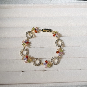 Macro detail of gold flower bracelet featuring colorful zircon petals and hollow rings