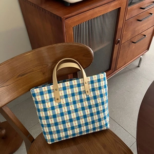 Blue plaid cotton tote bag with leather handles and floral accents on a wooden chair