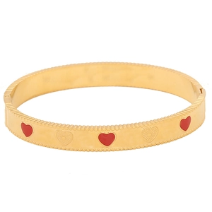 Close-up of golden vintage heart bangle with red heart and engraved pattern details