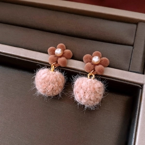 Detail von braunen Flockblumen-Ohrringen mit rosa Kunstfell-Pompon und Perle