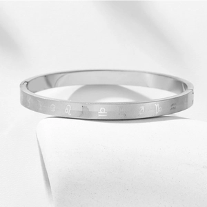 Macro shot of silver zodiac symbols and textured patterns on a titanium steel bangle