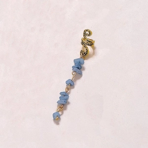 Detail of a golden ear cuff featuring a unique hanging blue natural stone pendant
