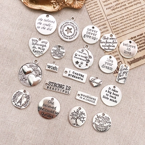 Flat lay of vintage silver alloy charms with motivational quotes for DIY jewelry making