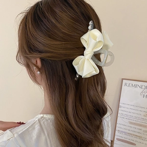 Elegant cream white satin bow hair claw with rhinestones on dark brown hair model