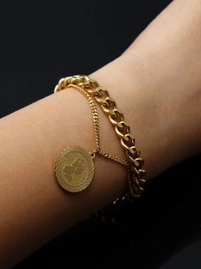 Macro detail of a double-layer 18K gold Cuban chain bracelet with Queen coin pendant