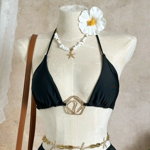 Detail of black bikini top with gold geometric ring connector on a cream mannequin