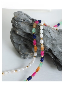 Detail of baroque pearls and colorful beads displayed on a dark natural rock base