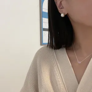Close-up of minimalist S925 silver ball earrings and purple glass necklace on model