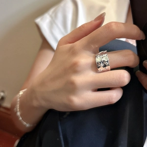 Hand wearing a wide silver S925 sterling silver hammered ring with four-pointed star design