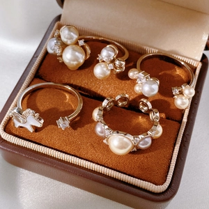 Detailed close-up of gold-plated rings with pearls and zircons in a brown velvet box