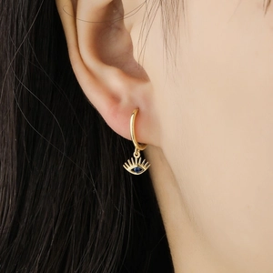 Evil eye drop earrings in gold with deep blue crystal on a model for a luxury look