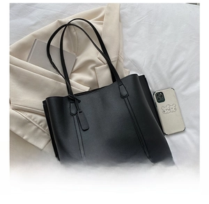 Detail of black faux leather tote bag with lychee texture and pleated side structure