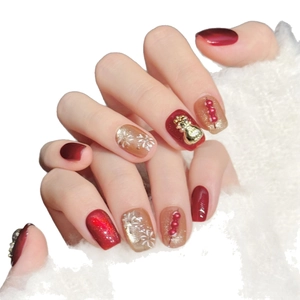 Uñas postizas festivas en rojo y dorado con bolsa de la suerte 3D y copos de nieve