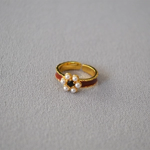 Close-up of vintage gold-plated ring with red enamel, pearls, and flower design