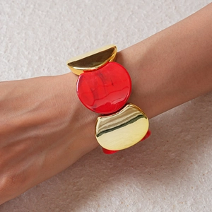 Dettaglio macro del bracciale elastico in acrilico rosso marmo e metallo dorato