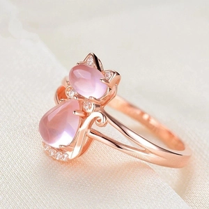 Elegant rose gold cat ring with pink quartz stones on white silk background