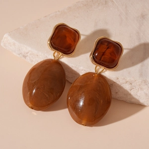 Detail view of tortoiseshell resin earrings with gold metal trim on stone base