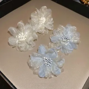 Elegant set of white and blue mesh flower earrings with pearl centers on display