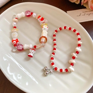 Detail of sweet beaded bracelets featuring red apple and silver cherry charms on tray